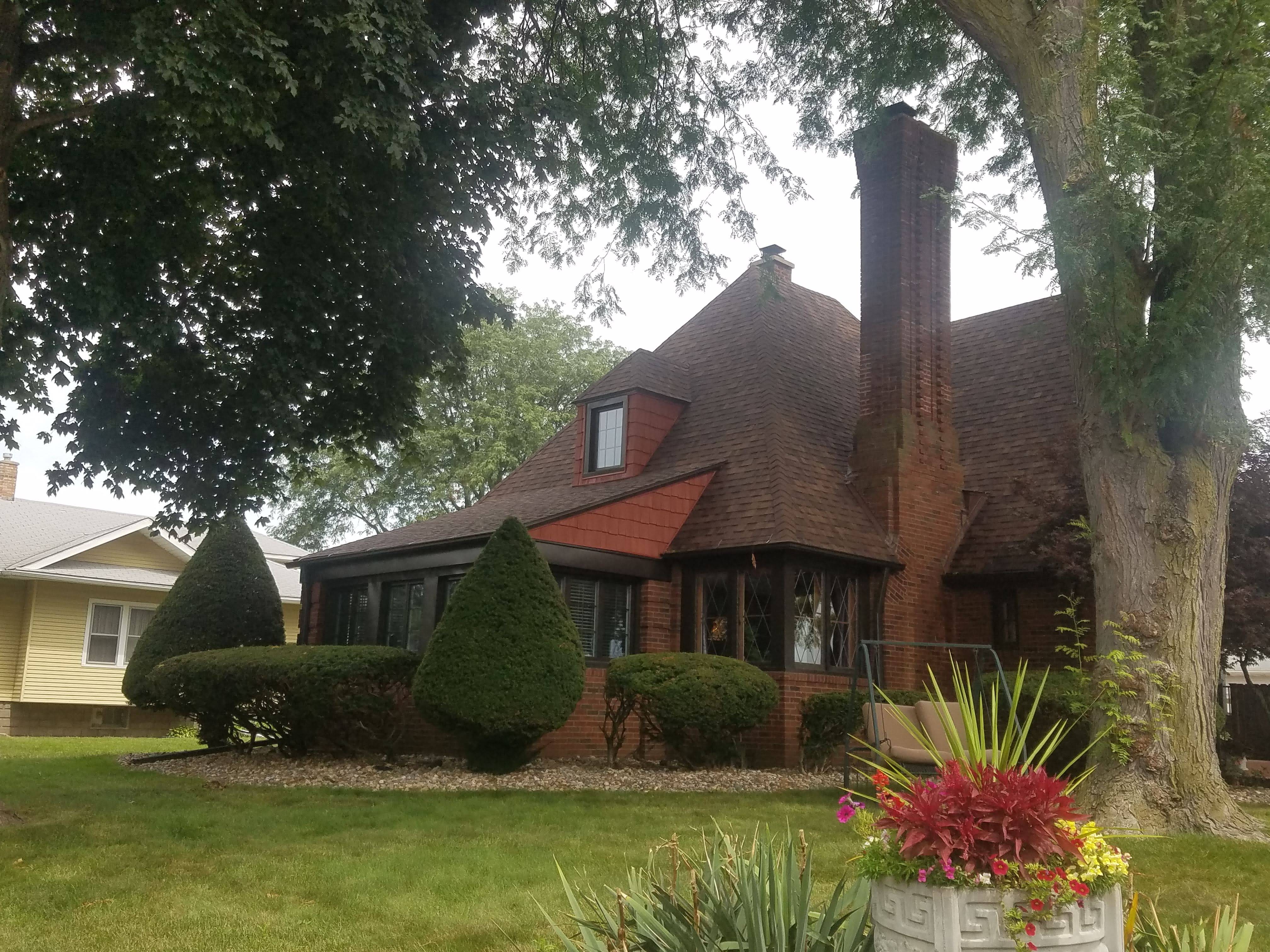 A large brick house with a tree in the background.