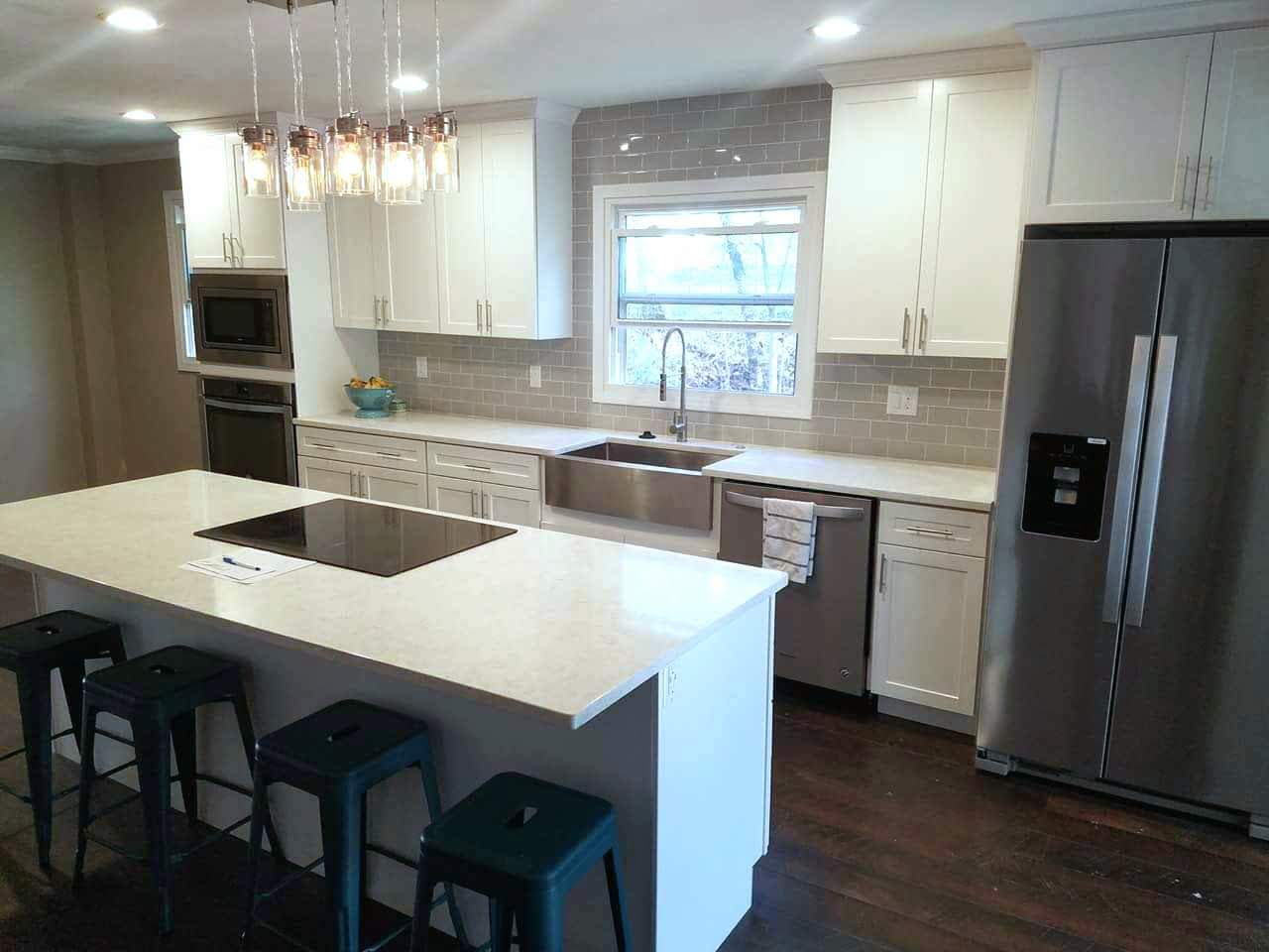 A kitchen with white cabinets and black counter tops.