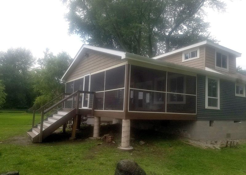 A house with a screened in porch and stairs.