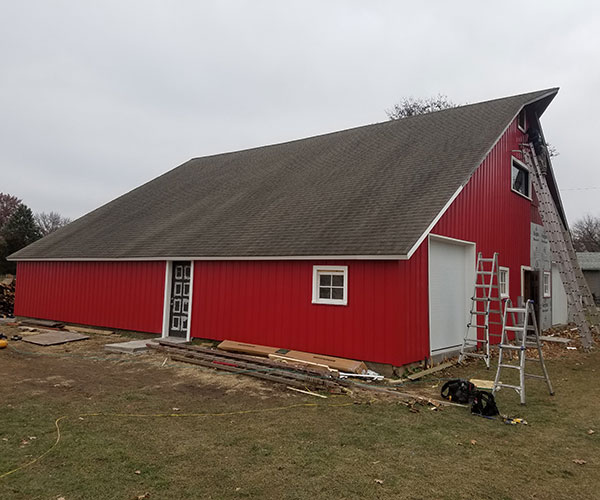 A red barn with a ladder in front of it.