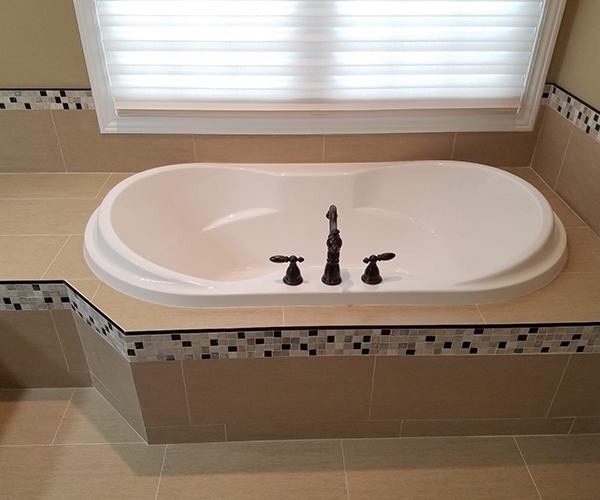 A bathroom with a large bathtub and tiled floor.