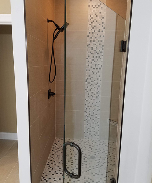 A shower with glass doors and a black handle.