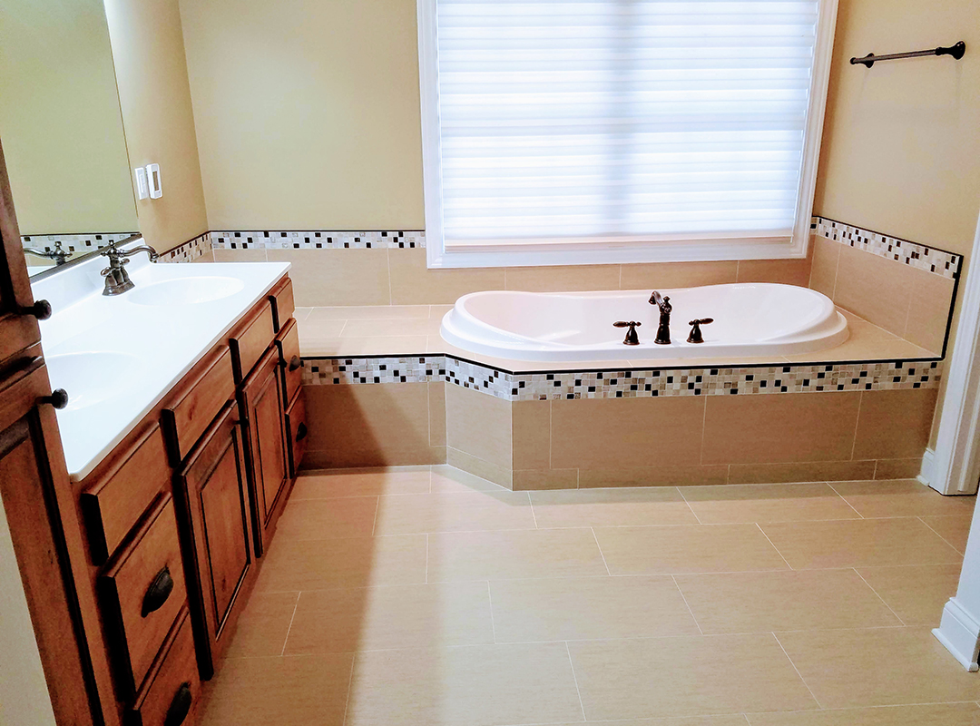 A bathroom with wooden drawers and tiled walls