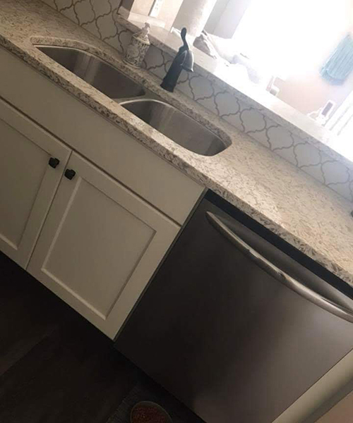 A kitchen with white cabinets and granite counter tops.