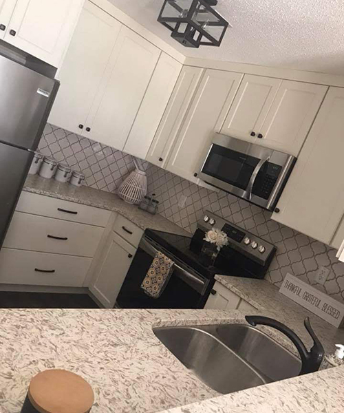 A kitchen with white cabinets and black appliances.