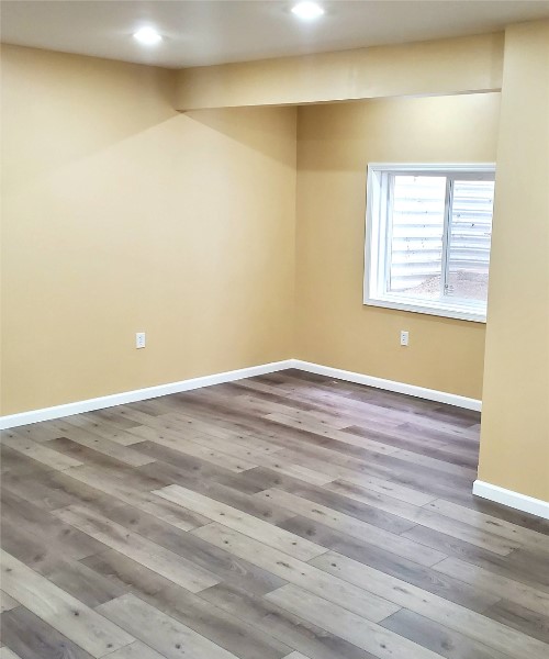 An empty room with wood floors and a window.