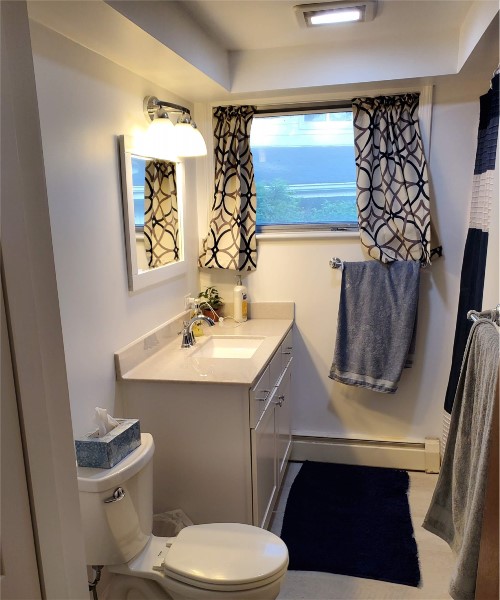 A bathroom with a toilet, sink and mirror.