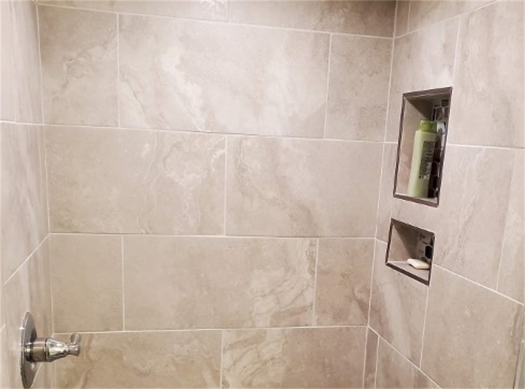 A bathroom with a tiled wall and a mirror