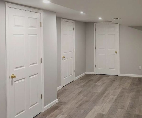 A white room with wood floors and white doors.