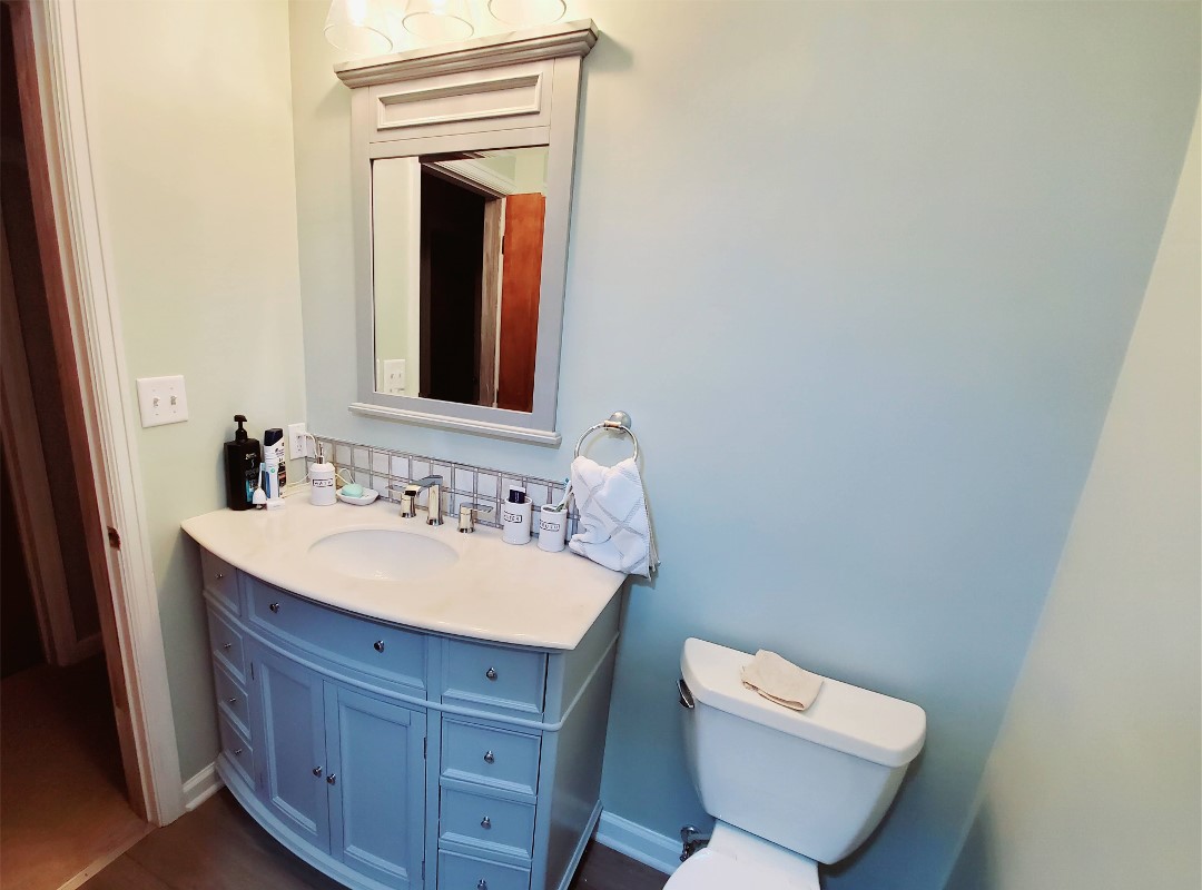 A bathroom with a blue vanity and toilet.