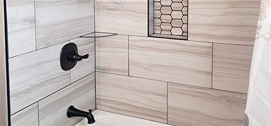 A white tiled shower with a black shower head.