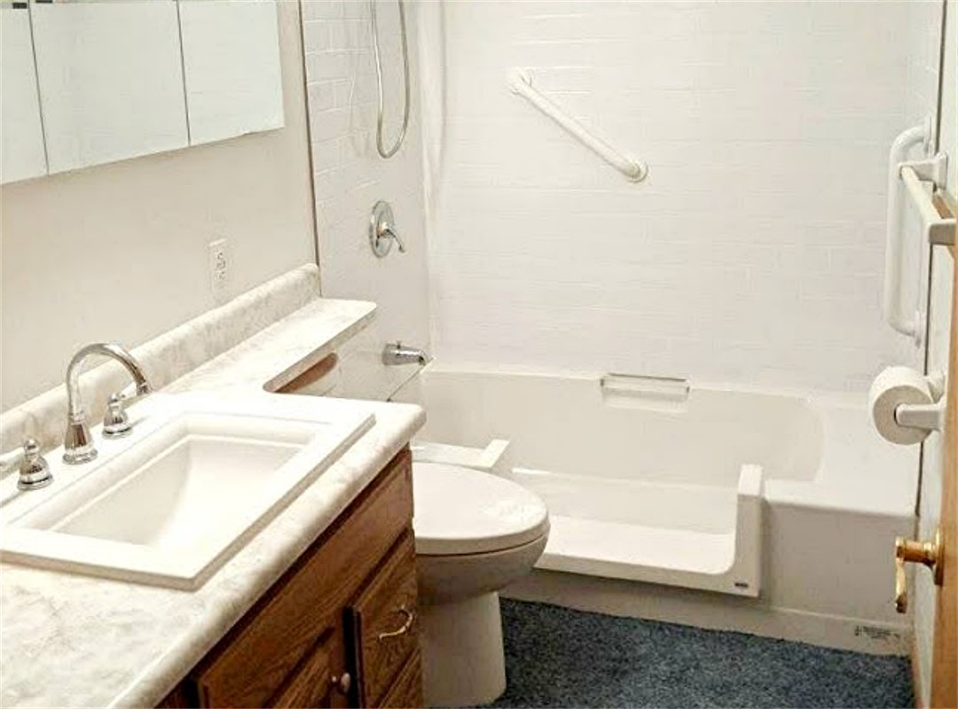 A bathroom with white walls and blue tile floors.