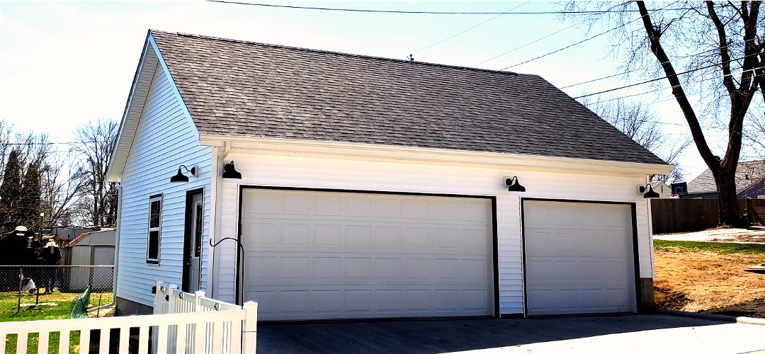 A white garage with two doors and a black roof.