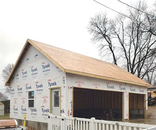 A house with some siding on it and trees in the background