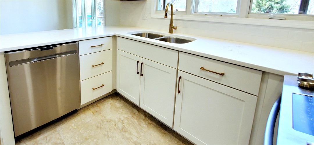 A kitchen with white cabinets and gold handles.