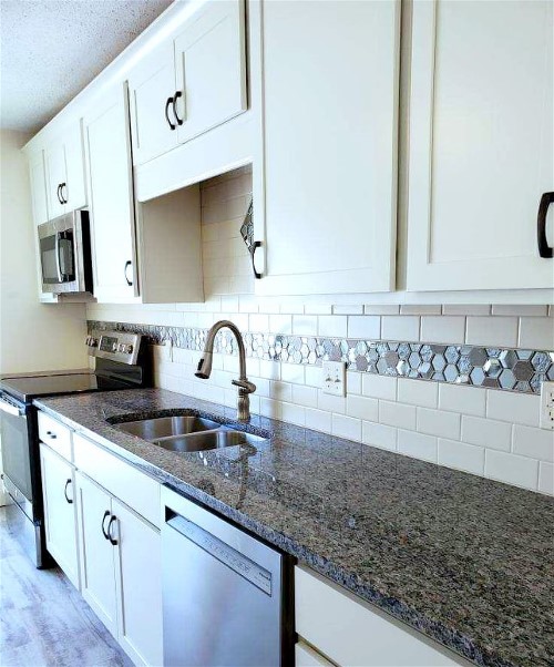 A kitchen with white cabinets and granite counter tops.