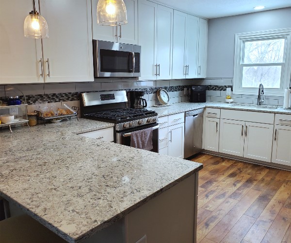 A kitchen with white cabinets and wood floors.