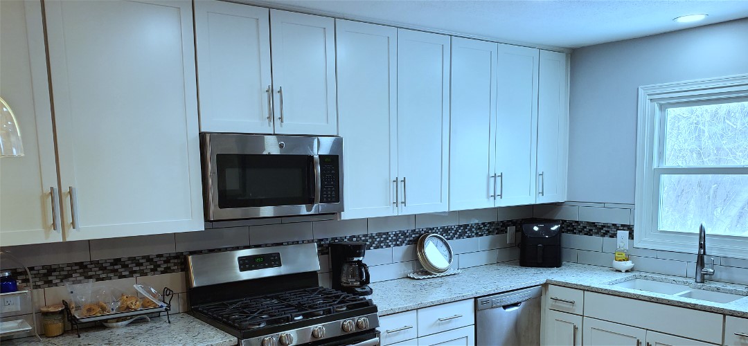 A kitchen with white cabinets and stainless steel appliances.