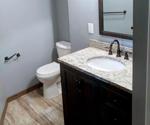 A bathroom with marble counter tops and wood floors.