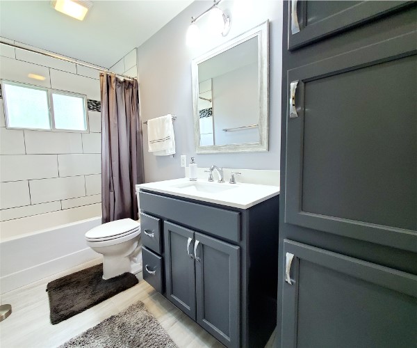 A bathroom with a sink, toilet and mirror.