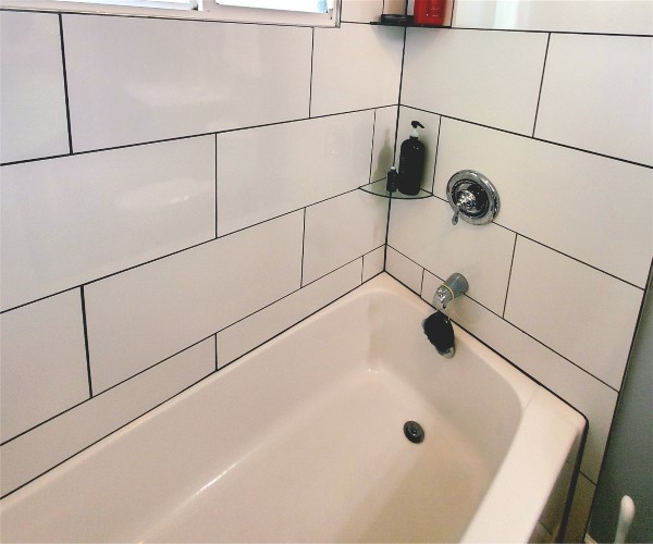 A bathtub with tiled walls