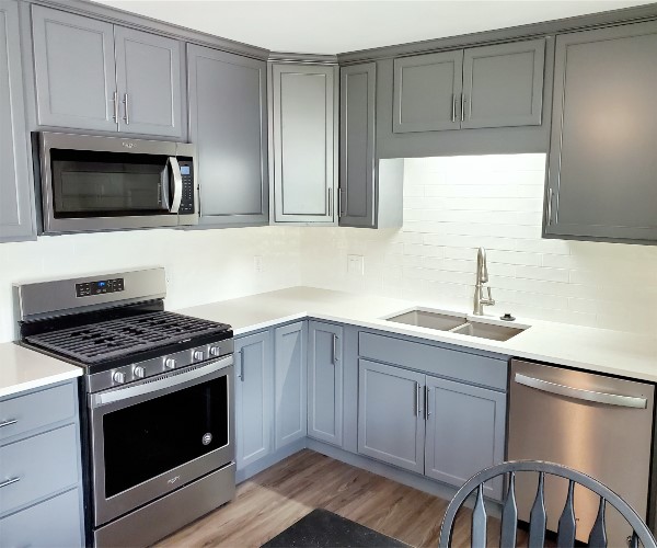 A kitchen with grey cabinets and white counters.