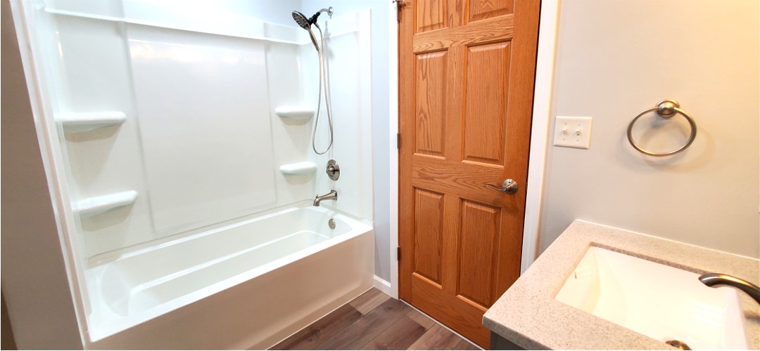 A bathroom with wood floors and white walls.