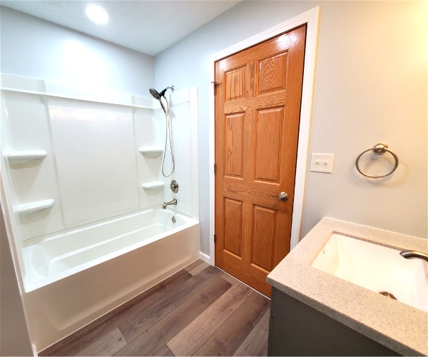 A bathroom with a sink, tub and wooden door.