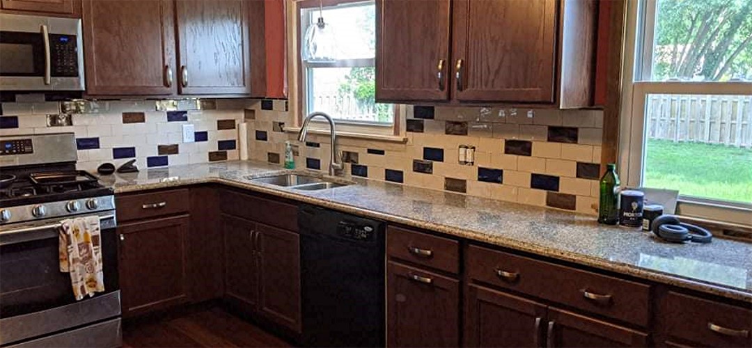 A kitchen with brown cabinets and tile backsplash.