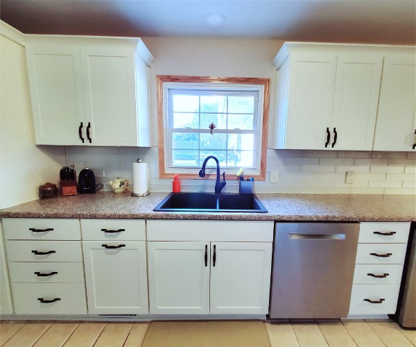 A kitchen with white cabinets and a sink.