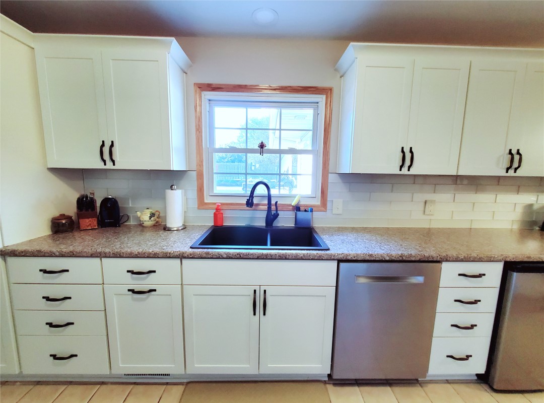 A kitchen with white cabinets and black sink.