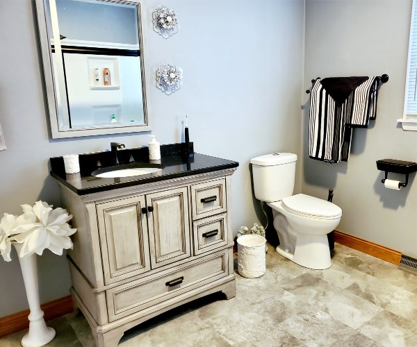 A bathroom with a sink, toilet and mirror.