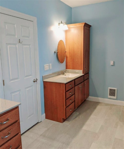 A bathroom with blue walls and white counter tops.