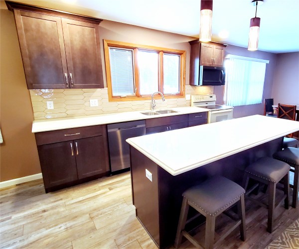 A kitchen with brown cabinets and white counter tops.