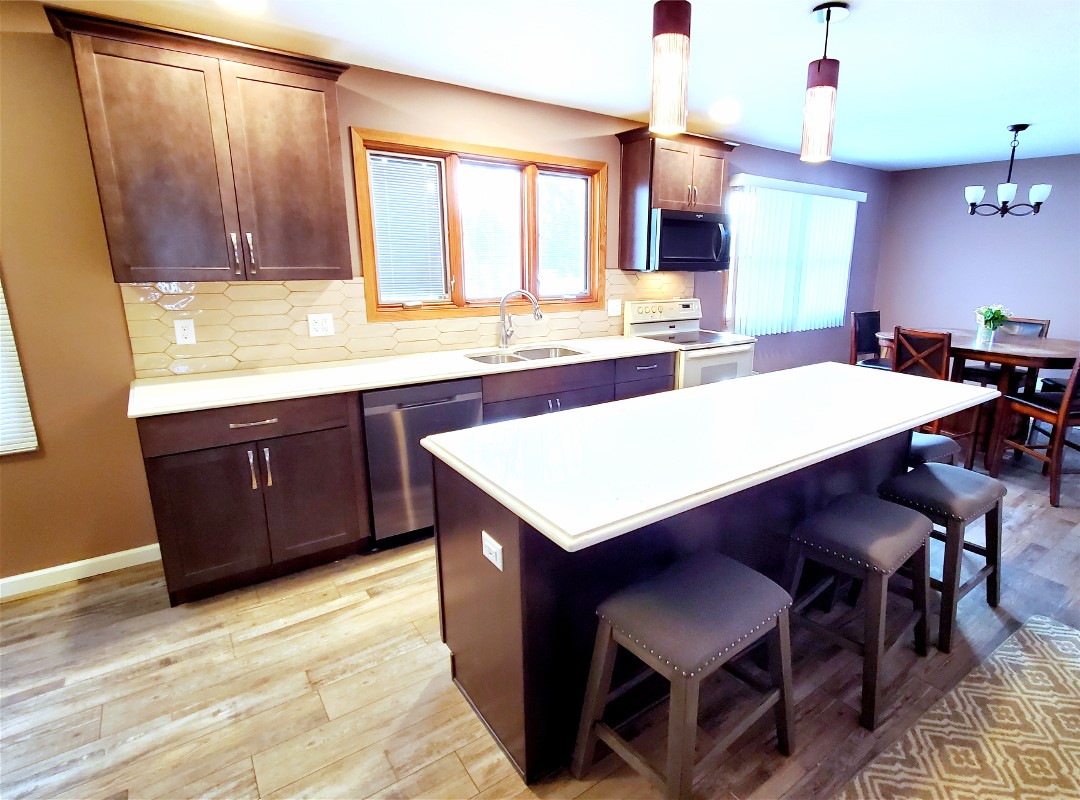 A kitchen with brown cabinets and white counter tops.