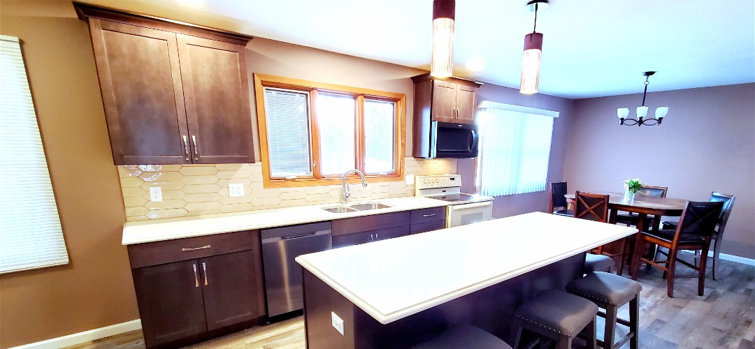 A kitchen with brown cabinets and white counter tops.