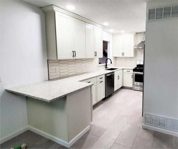 A kitchen with white cabinets and black appliances.