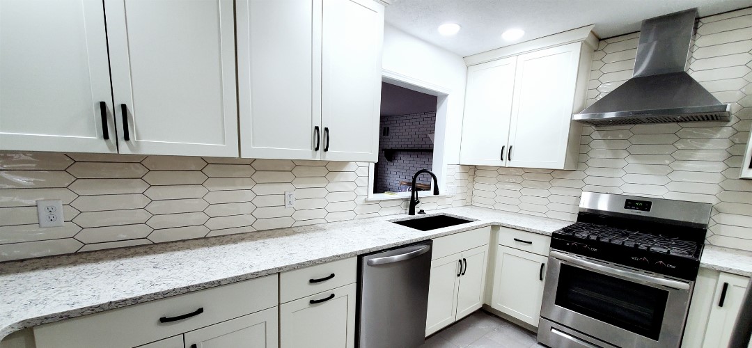 A kitchen with white cabinets and black appliances.