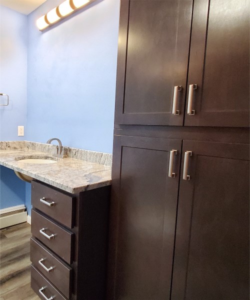 A bathroom with brown cabinets and a sink.