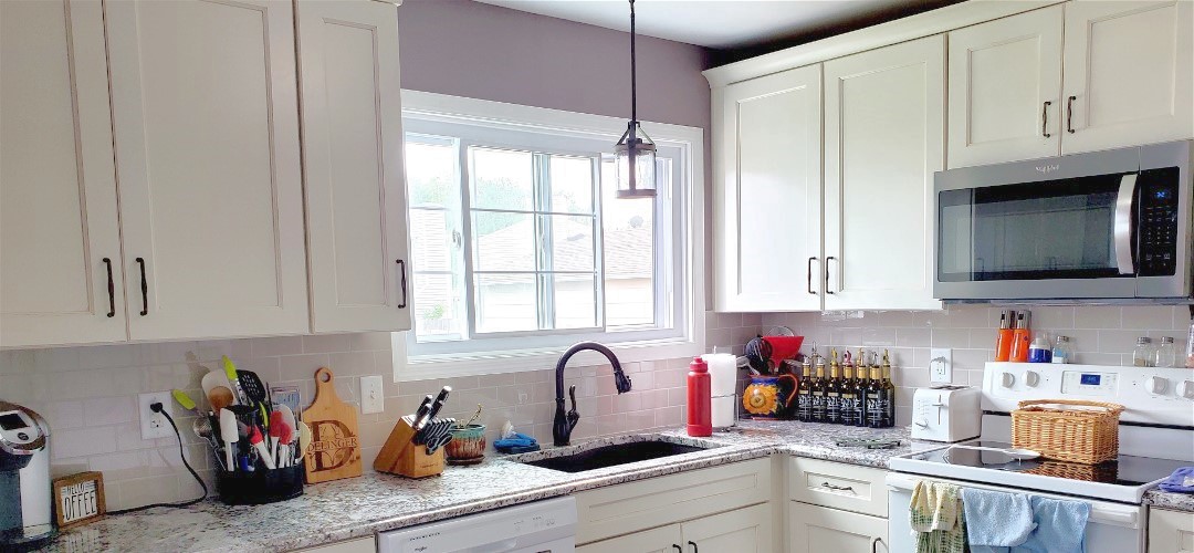 A kitchen with white cabinets and black sink.