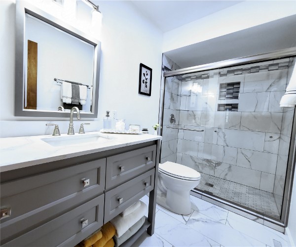 A bathroom with marble walls and floors, and white fixtures.