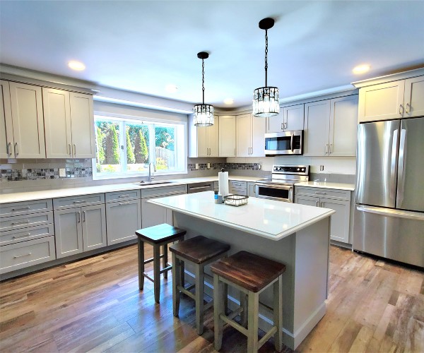 A kitchen with white cabinets and wooden floors