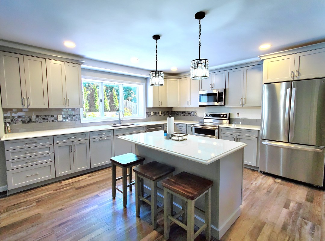 A kitchen with white cabinets and wooden floors