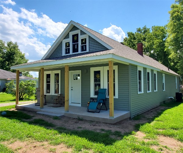 A small house with a porch and a blue door.