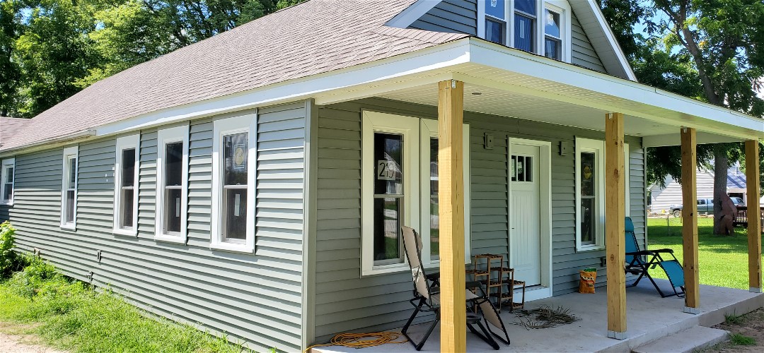 A house with a porch and chairs outside.