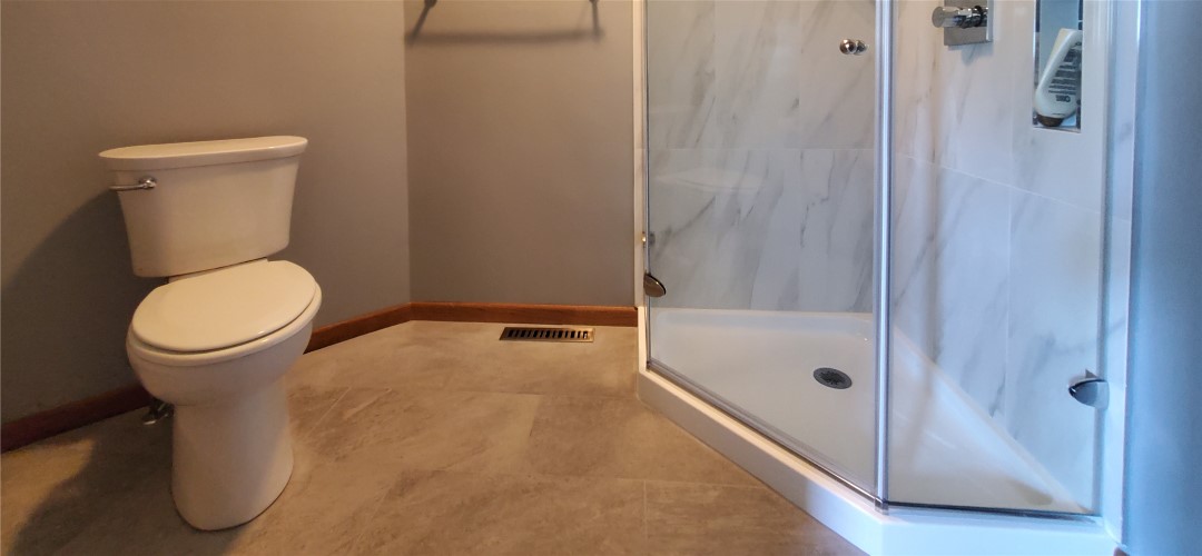 A bathroom with a walk in shower and beige tile floor.