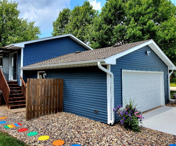 A blue house with a white garage door and a wooden fence.