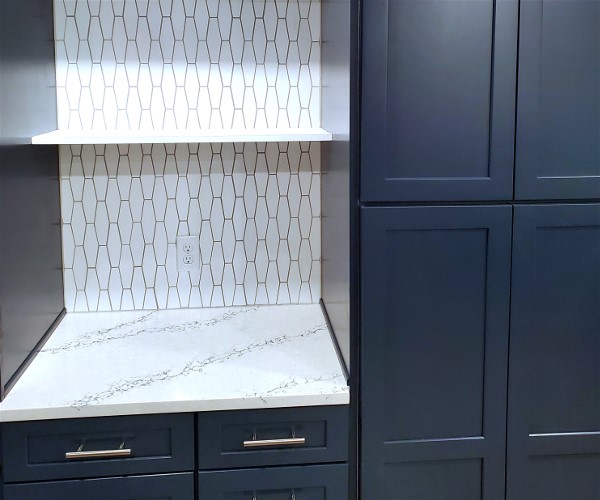 A kitchen with blue cabinets and white counter tops.