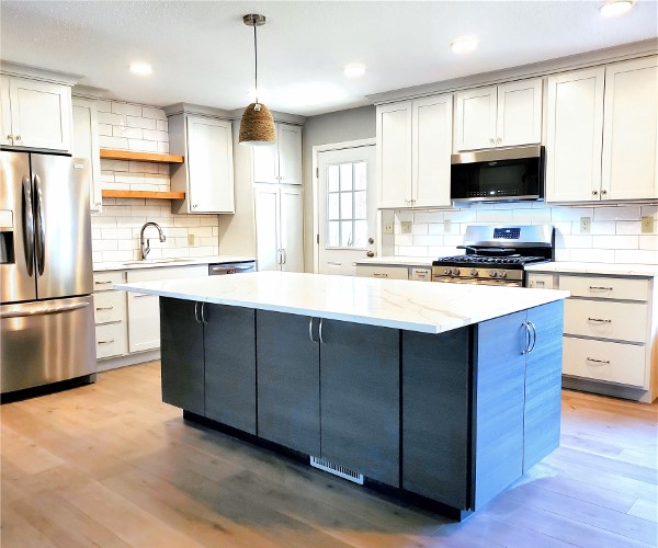 A kitchen with white cabinets and wood floors.