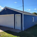 A blue and white garage with a door open.